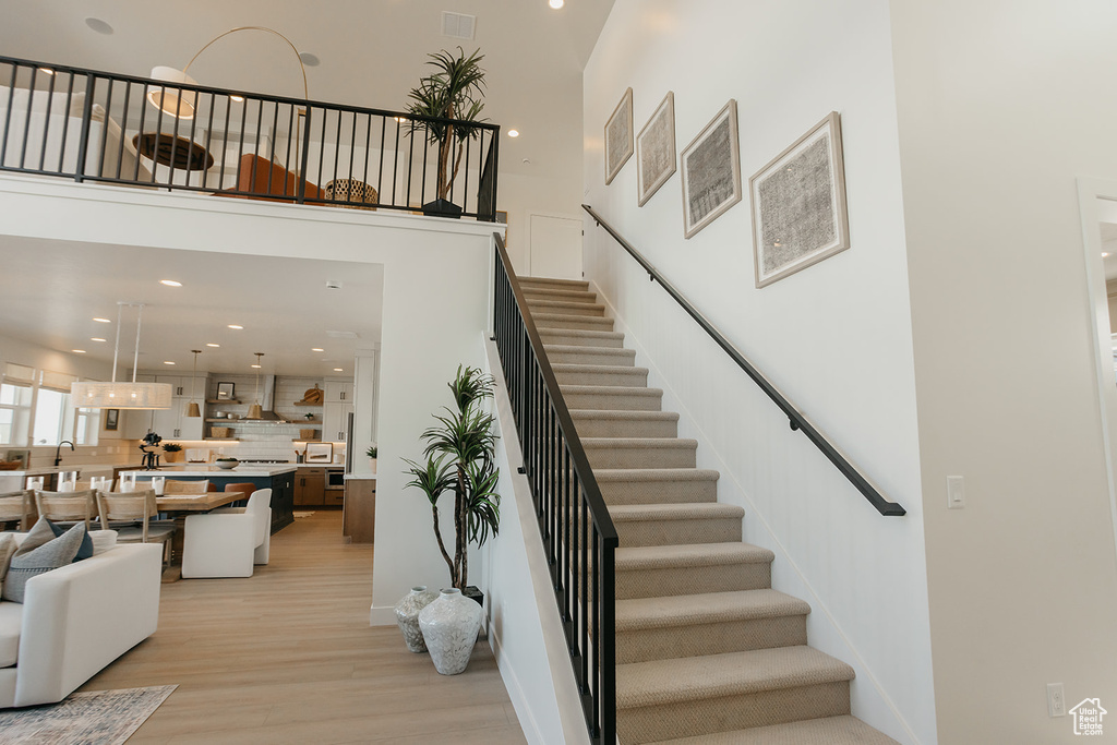 Stairway featuring wood finished floors, a high ceiling, and recessed lighting