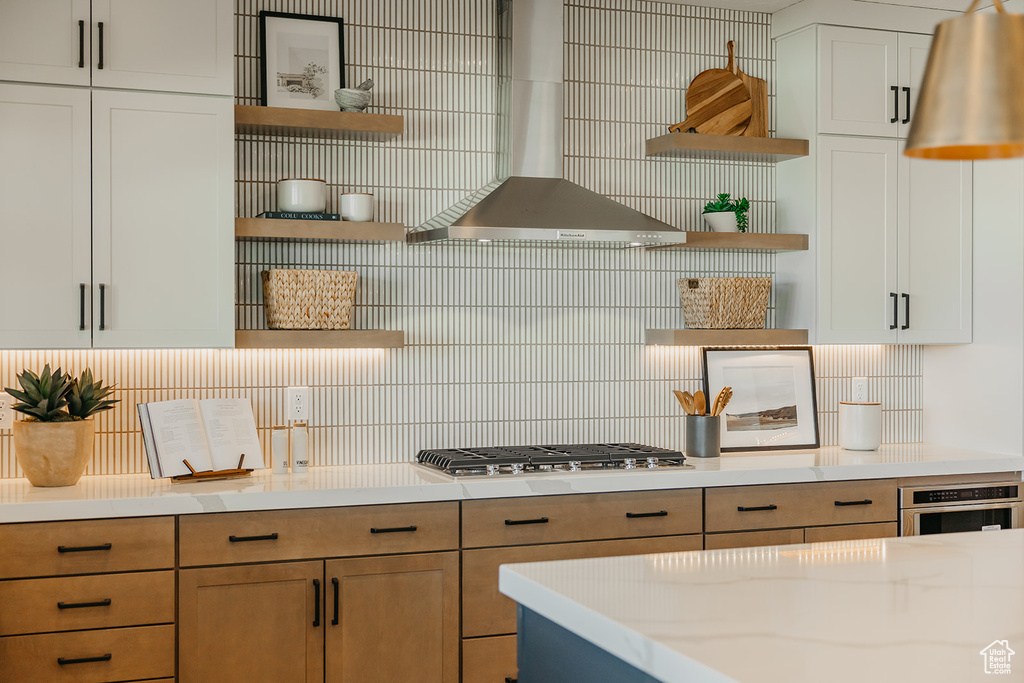 Kitchen with open shelves, wall chimney range hood, stainless steel appliances, and tasteful backsplash