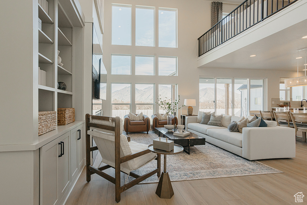 Living area featuring a towering ceiling, light wood-style floors, and a mountain view