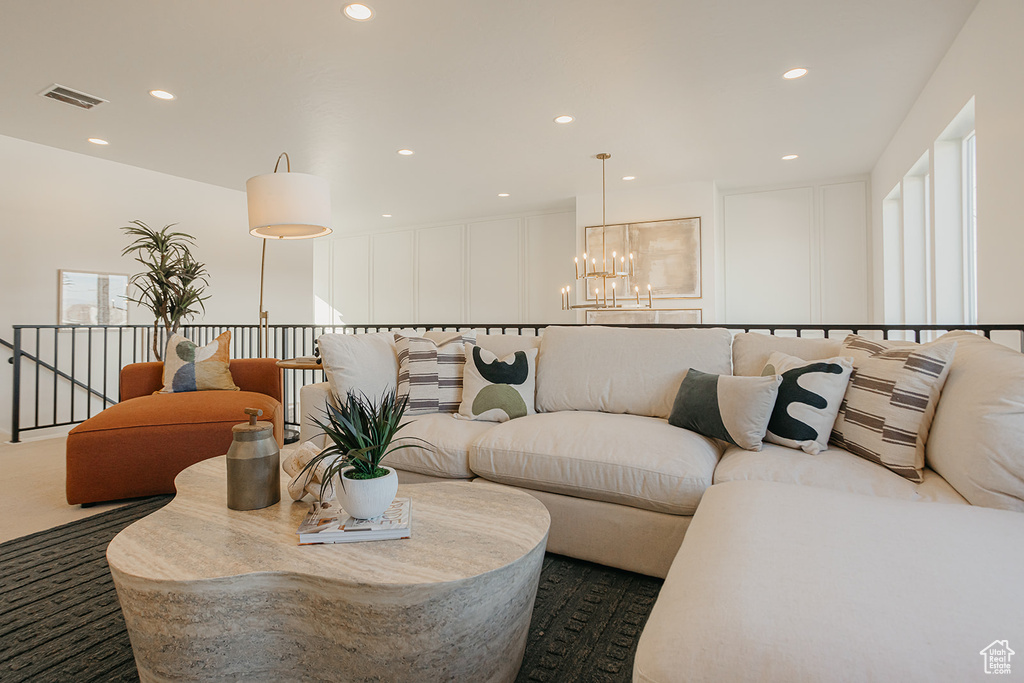 Living room with a chandelier, recessed lighting, and a decorative wall