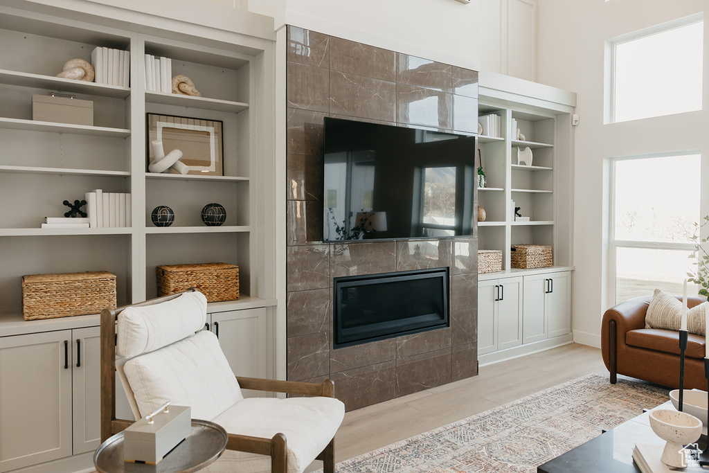Living room featuring a high end fireplace, built in features, and light wood-style flooring