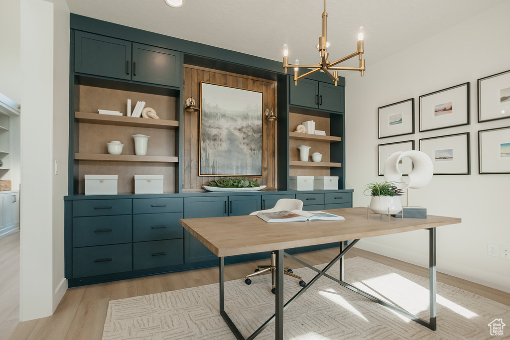 Office area featuring a chandelier, light wood-style flooring, and built in shelves