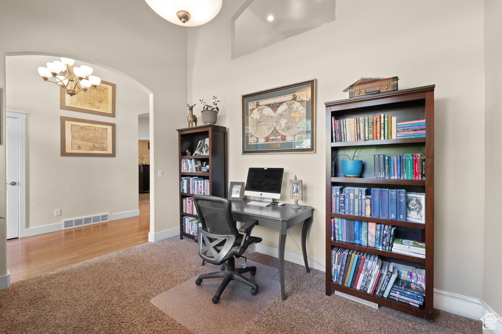 Office area featuring arched walkways, carpet flooring, and a chandelier