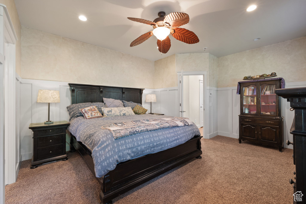Carpeted bedroom with wainscoting, a decorative wall, recessed lighting, and ceiling fan