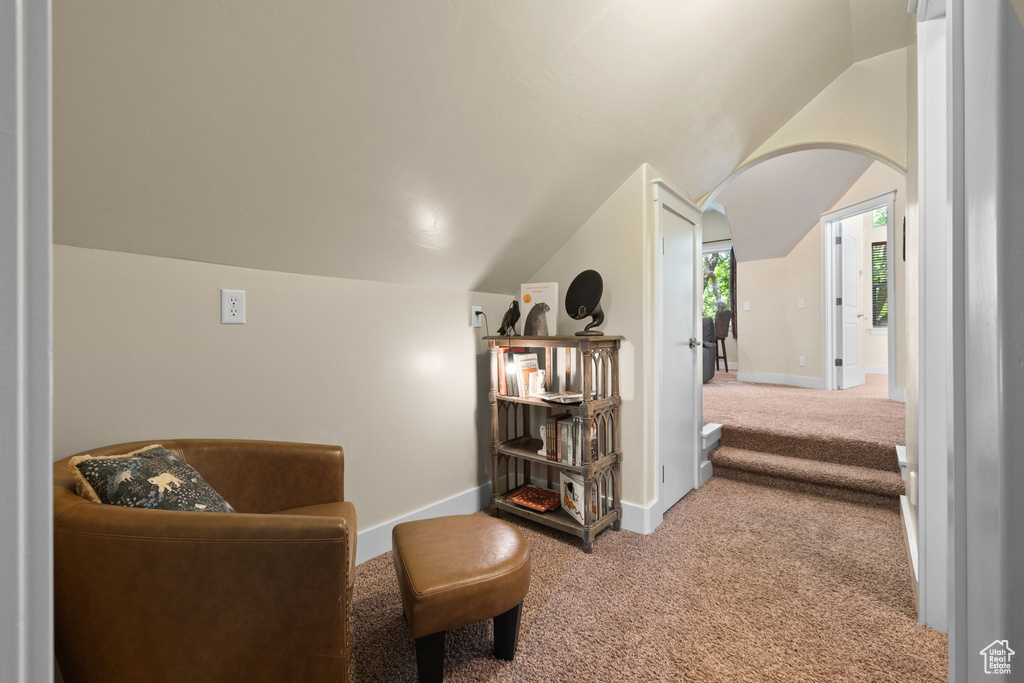 Sitting room featuring carpet flooring, arched walkways, and vaulted ceiling