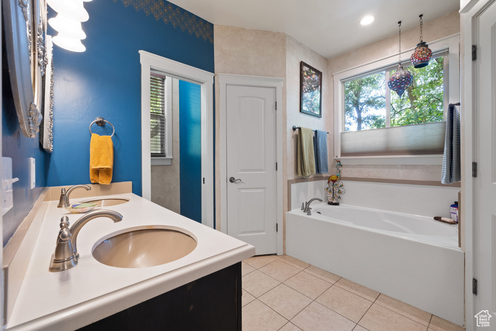 Full bath with tile patterned flooring, double vanity, and a garden tub