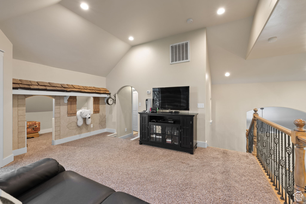 Living area with lofted ceiling, arched walkways, carpet, and recessed lighting
