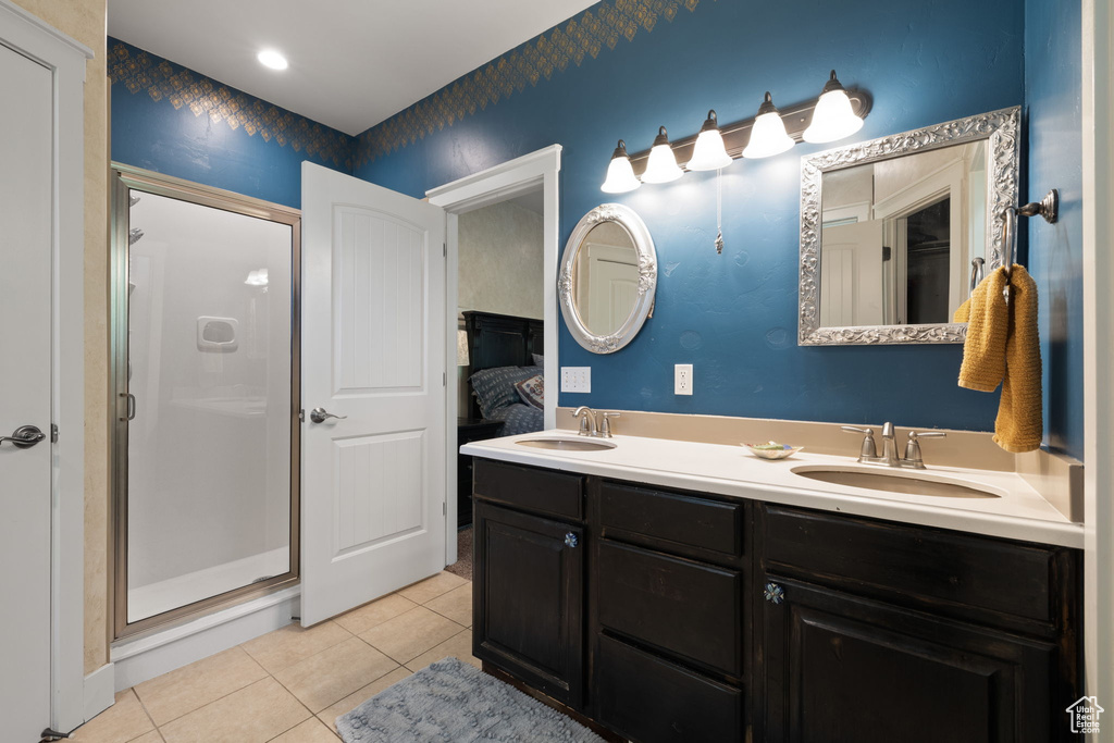 Ensuite bathroom featuring tile patterned floors, double vanity, and a shower stall