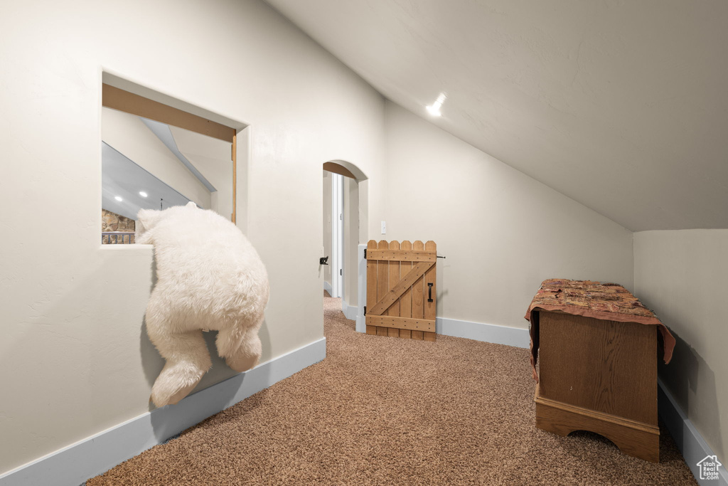 Bonus room featuring vaulted ceiling, arched walkways, and carpet flooring
