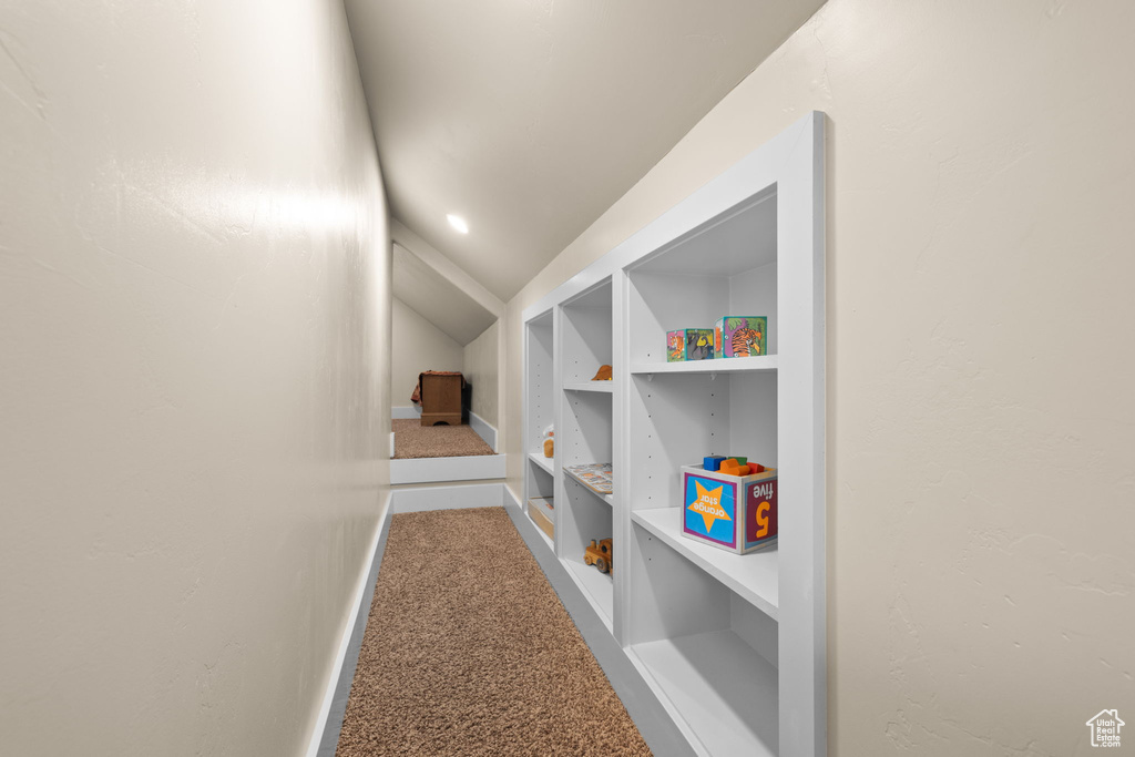 Hall with carpet floors, lofted ceiling, and built in shelves