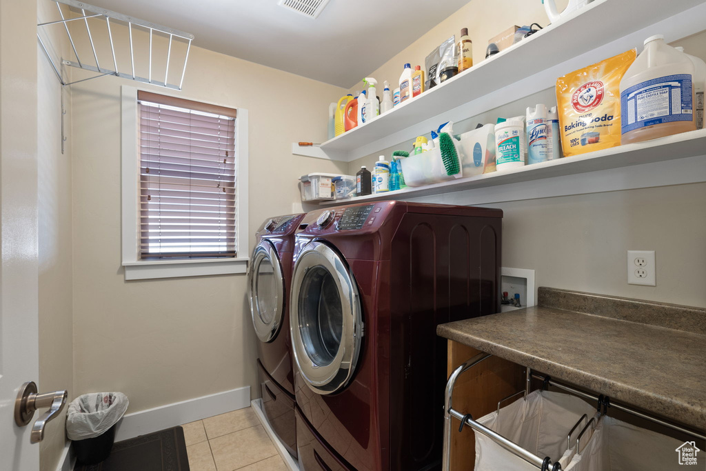 Laundry area with washing machine and dryer and light tile patterned flooring