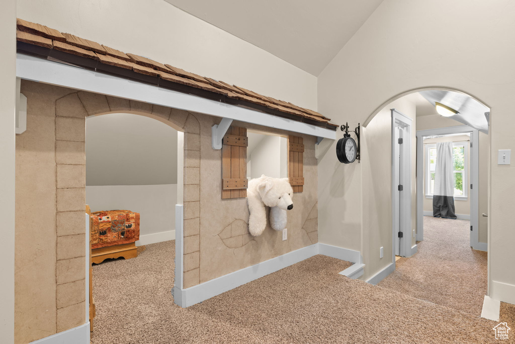 Interior space with arched walkways, carpet floors, and vaulted ceiling