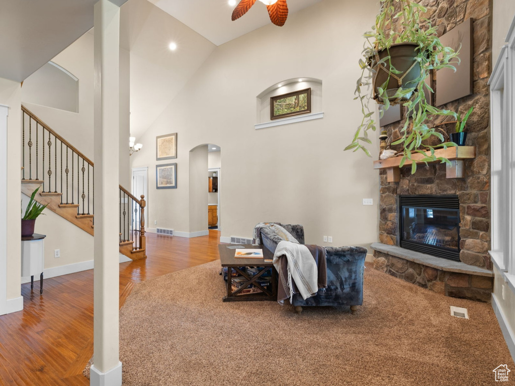 Living room featuring a ceiling fan, wood finished floors, arched walkways, a fireplace, and stairs