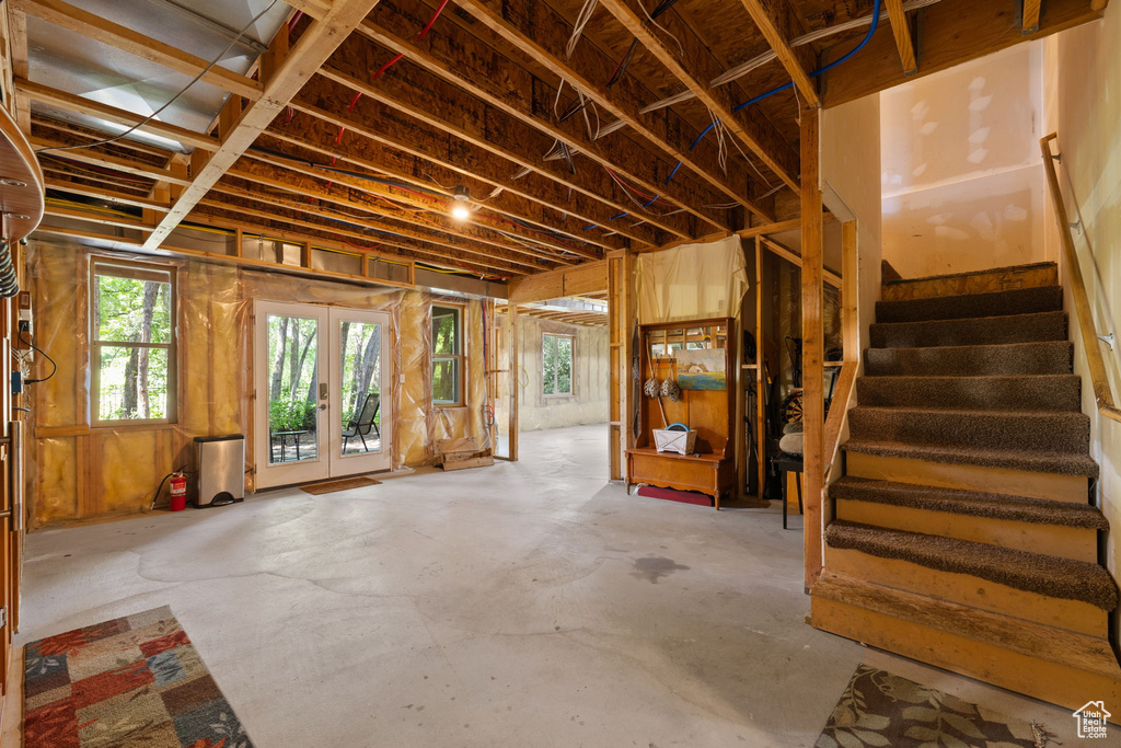 Misc room featuring stairway, healthy amount of natural light, concrete flooring, and french doors