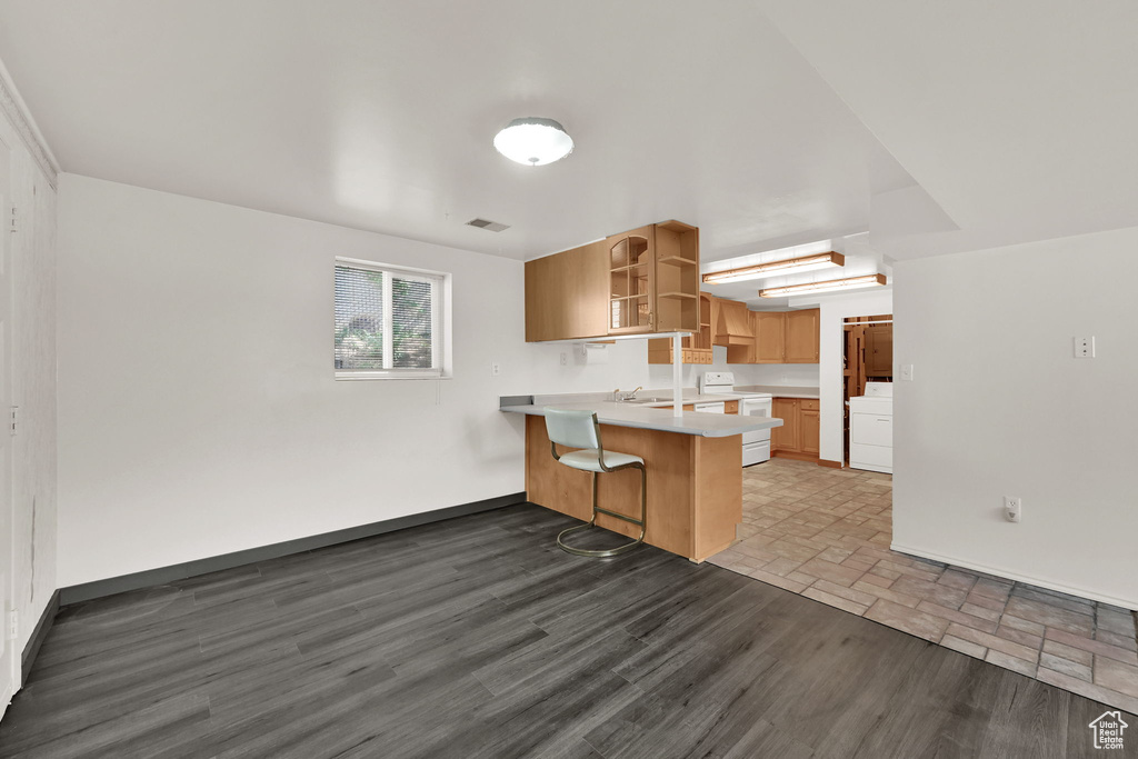 Kitchen with a peninsula, white range with electric cooktop, open shelves, a kitchen breakfast bar, and light countertops