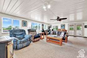 Living room featuring plenty of natural light, a ceiling fan, carpet floors, and wooden ceiling