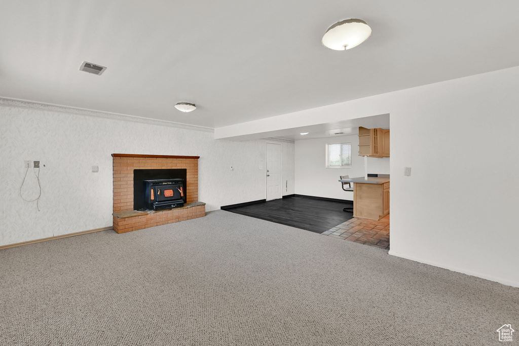 Unfurnished living room featuring a wood stove and carpet floors