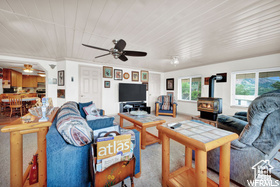 Carpeted living room with a wood stove, a ceiling fan, and wood ceiling