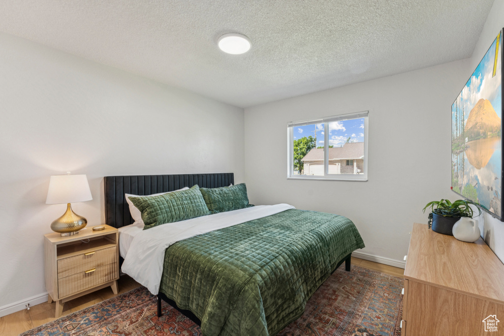 Bedroom with a textured ceiling and wood finished floors