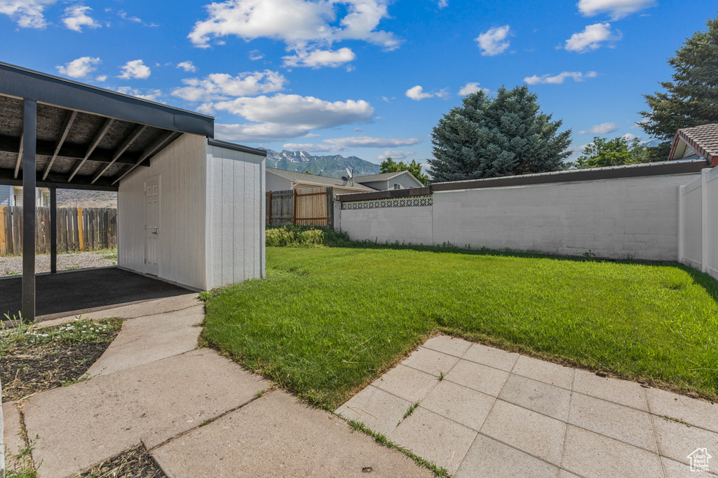 Fenced backyard featuring a mountain view, a patio, and a storage unit