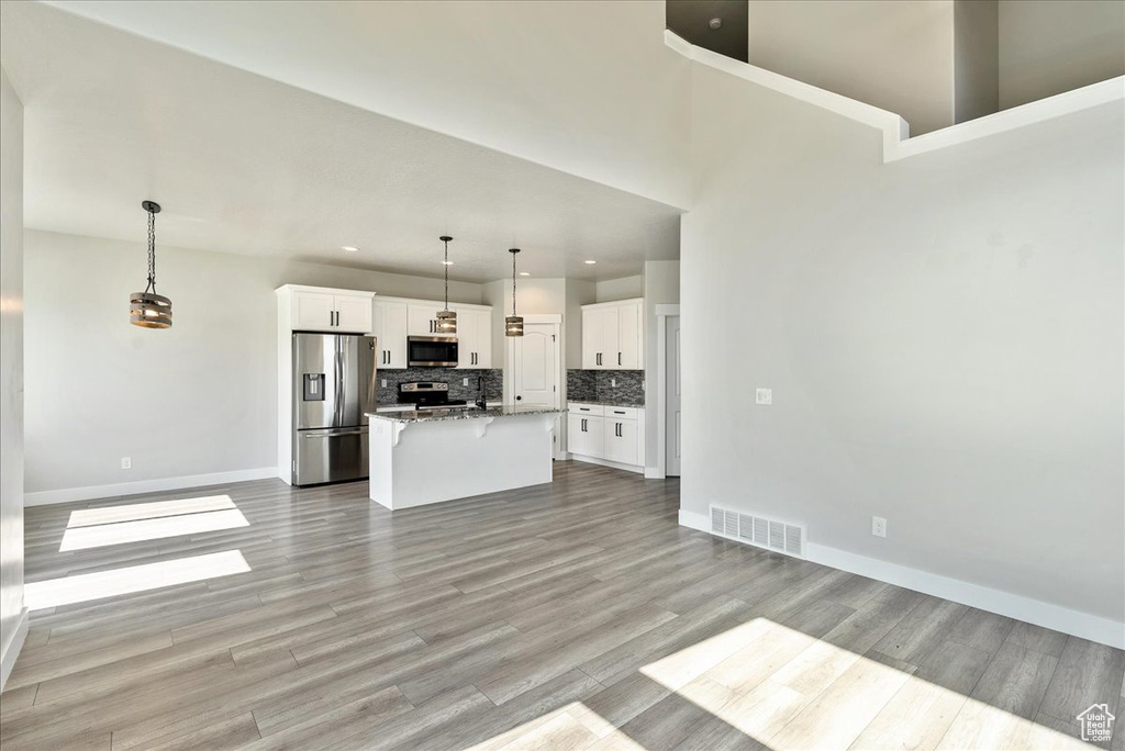 Kitchen featuring stainless steel appliances, white cabinets, a kitchen breakfast bar, decorative backsplash, and a kitchen island