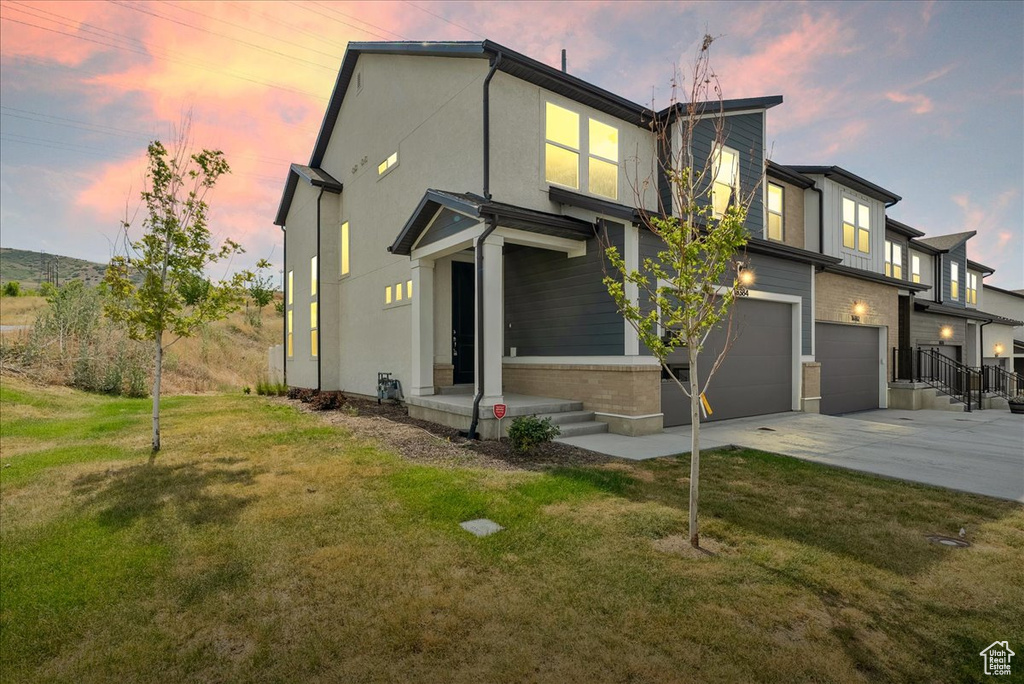 View of front of home featuring a garage, driveway, a front lawn, and brick siding