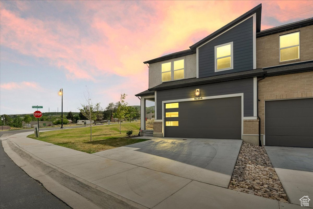 View of front of home featuring a garage, concrete driveway, and a front yard