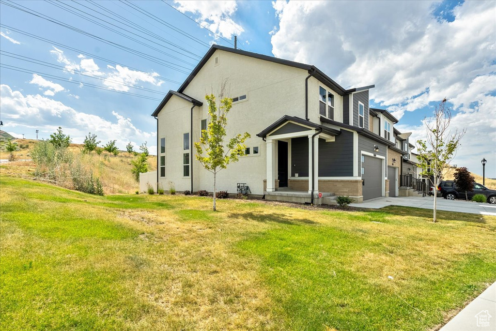 Back of property featuring an attached garage, driveway, and a lawn