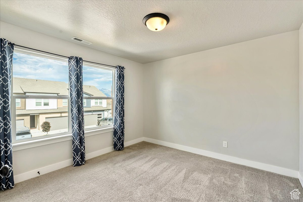 Carpeted empty room featuring a textured ceiling
