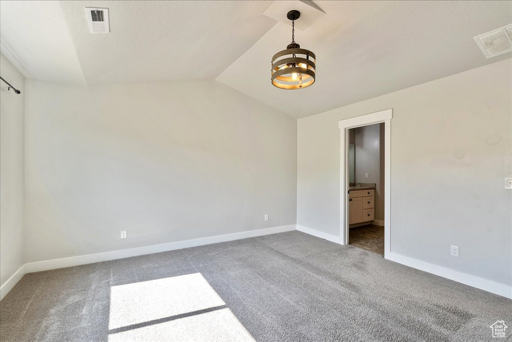 Unfurnished bedroom featuring vaulted ceiling, carpet flooring, and ensuite bath