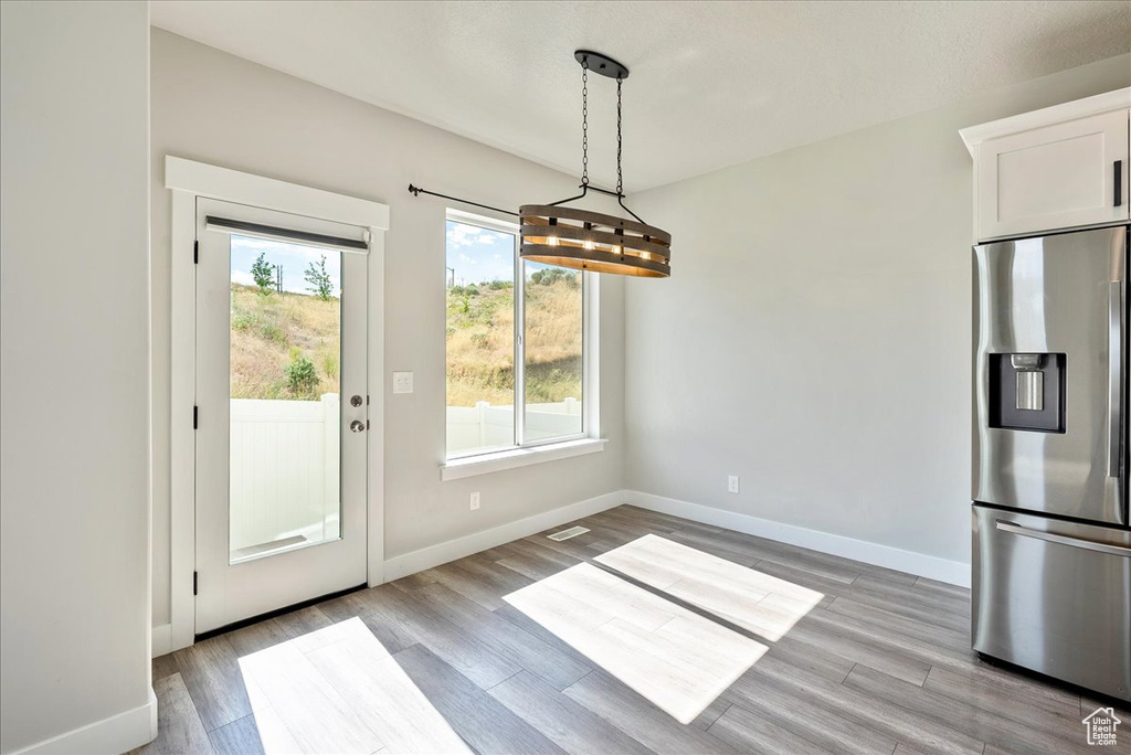 Unfurnished dining area with light wood-style flooring and baseboards