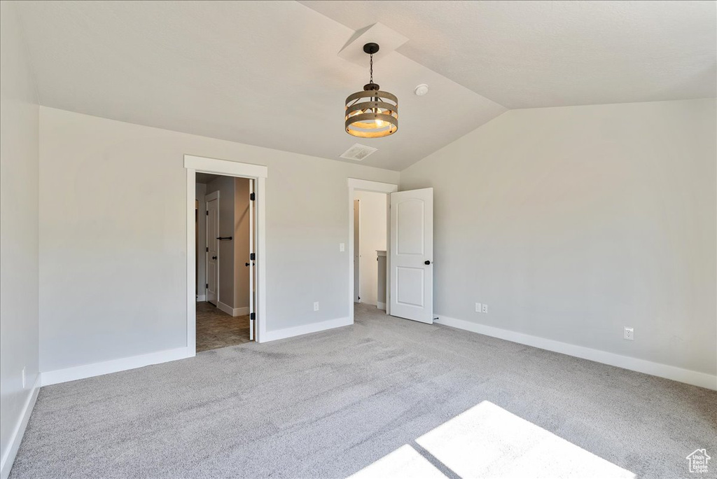 Unfurnished bedroom with vaulted ceiling and light colored carpet