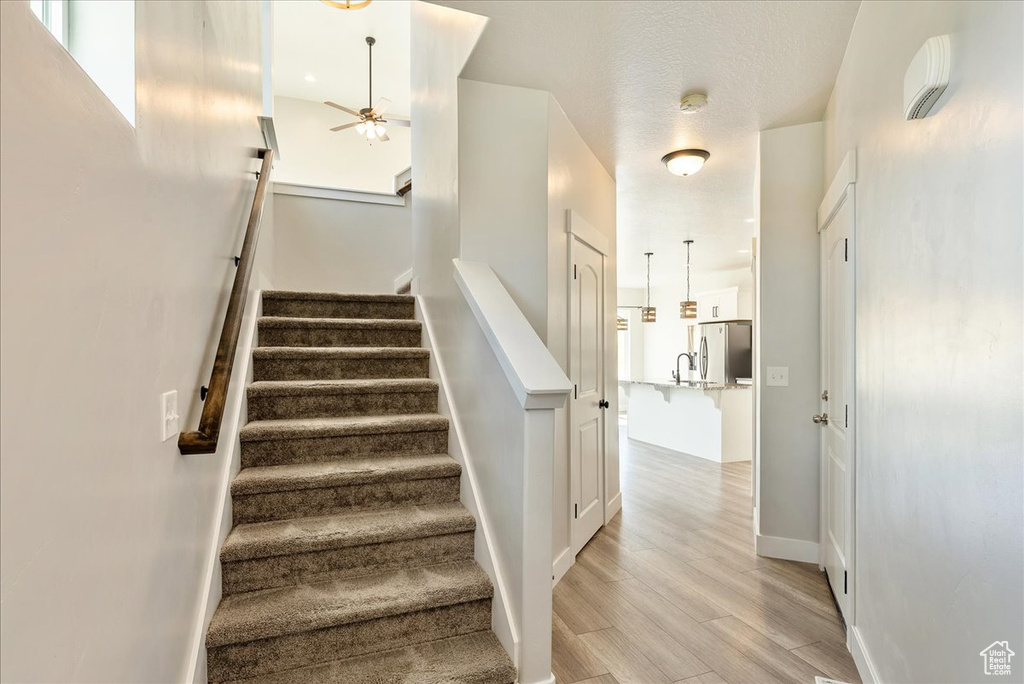 Stairway featuring ceiling fan and wood finished floors