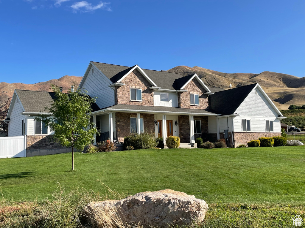 View of front of home with stone siding, a mountain view, and a porch