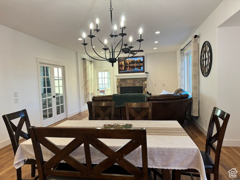 Dining room with wood finished floors, recessed lighting, a chandelier, and a fireplace