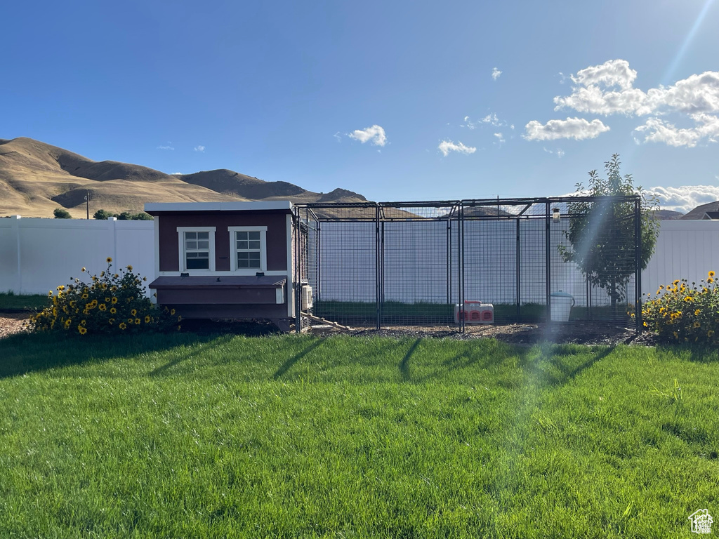 Back of house with a fenced backyard, an outdoor structure, exterior structure, and a mountain view