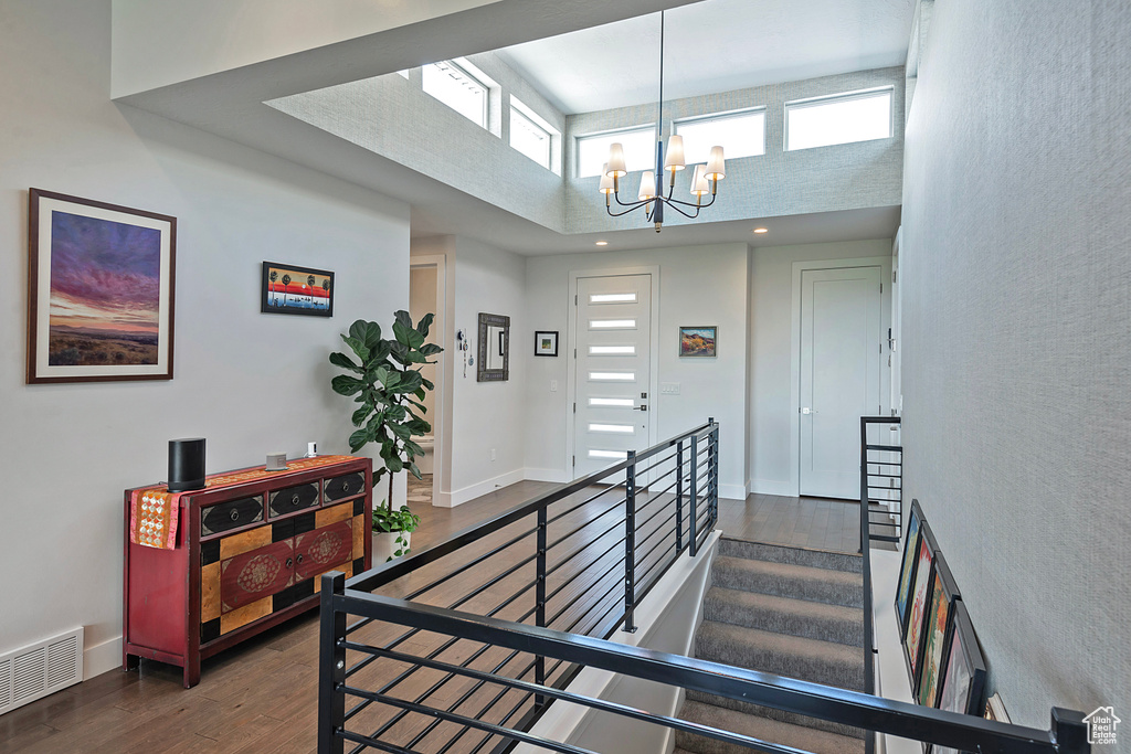 Stairway featuring a high ceiling, a chandelier, and wood finished floors