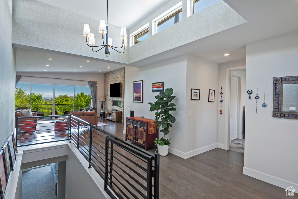 Hall featuring a high ceiling, healthy amount of natural light, dark wood finished floors, a chandelier, and recessed lighting