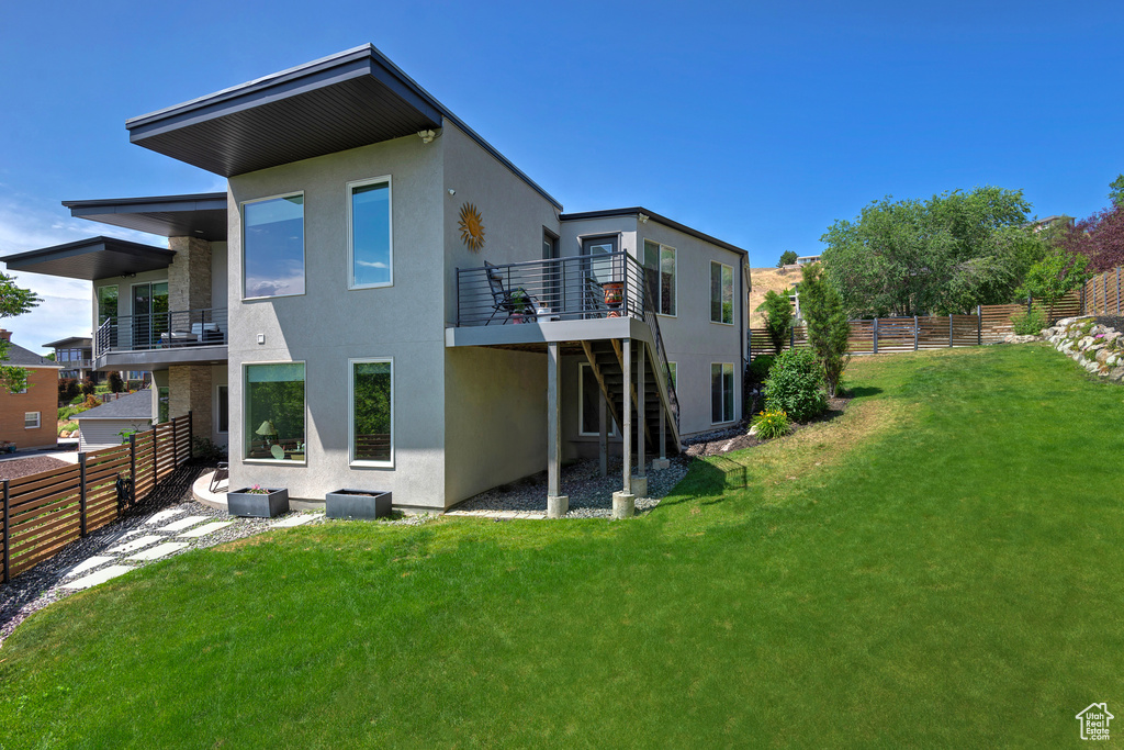 Back of property featuring stucco siding, stairs, a fenced backyard, and a deck