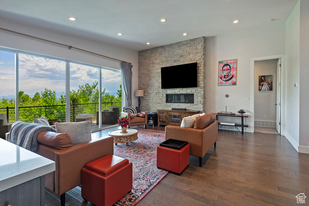 Living area featuring healthy amount of natural light, dark wood-type flooring, recessed lighting, and a stone fireplace