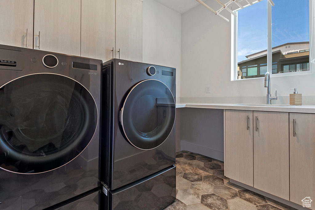 Laundry room with cabinet space, separate washer and dryer, and stone finish floors