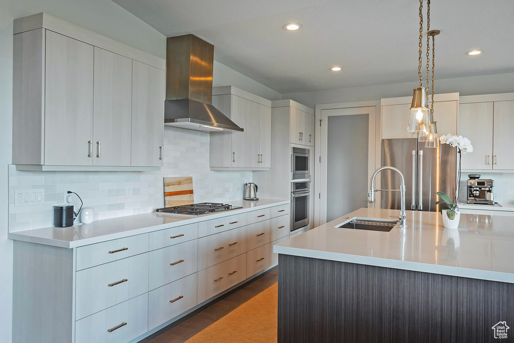 Kitchen featuring wall chimney exhaust hood, stainless steel appliances, light countertops, tasteful backsplash, and recessed lighting