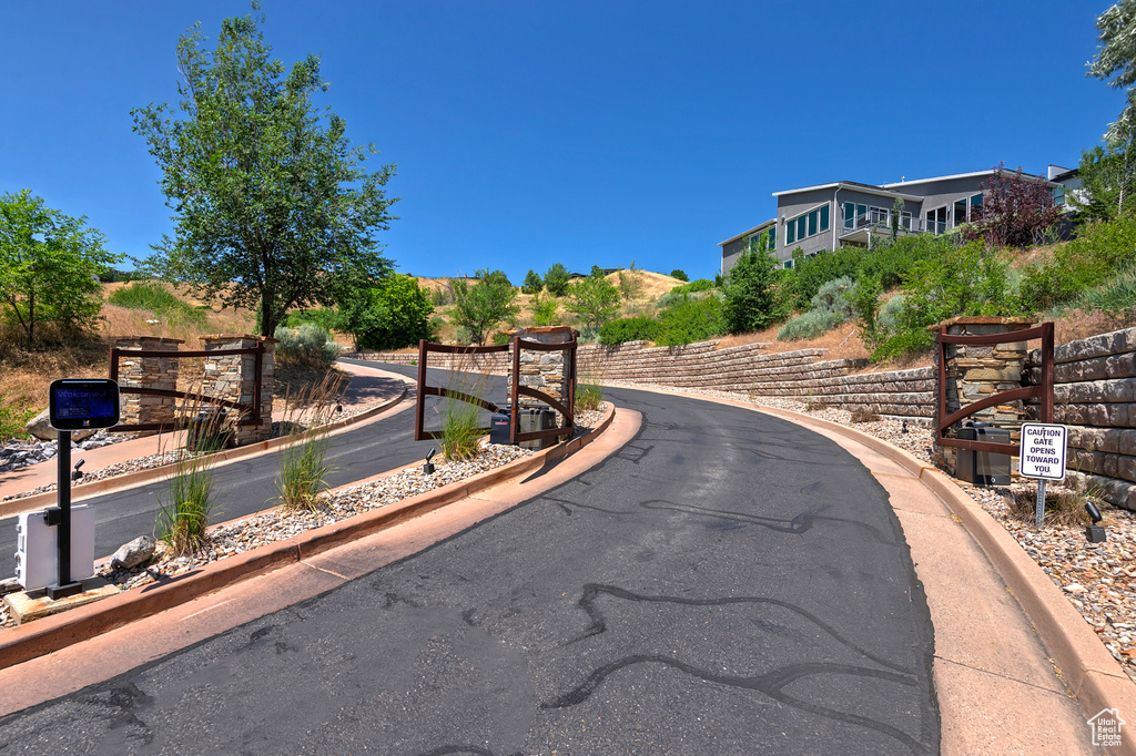 View of asphalt road with curbs and a gated entry