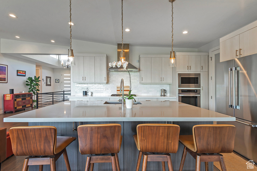 Kitchen featuring island exhaust hood, stainless steel appliances, recessed lighting, decorative backsplash, and light countertops