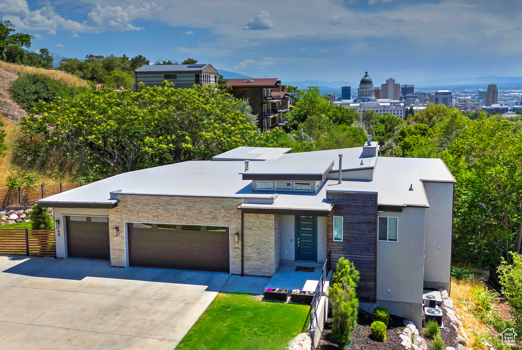 Modern home with concrete driveway, an attached garage, and stone siding