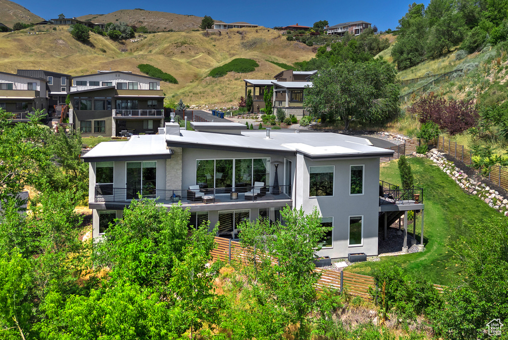 Back of property featuring stucco siding, a balcony, and a mountain view