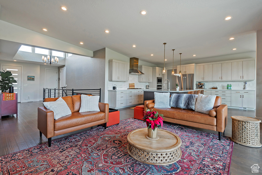 Living area with a chandelier, lofted ceiling, dark wood-style floors, and recessed lighting