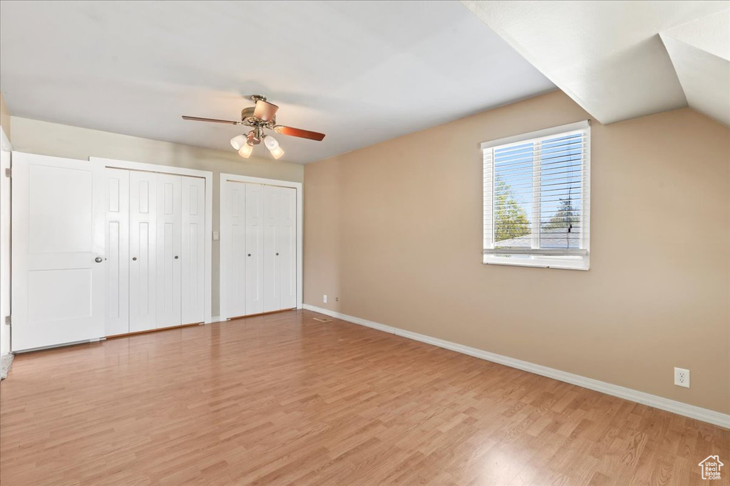 Unfurnished bedroom with multiple closets, light wood-style flooring, and a ceiling fan