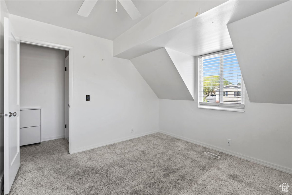 Additional living space featuring carpet flooring, a ceiling fan, and vaulted ceiling