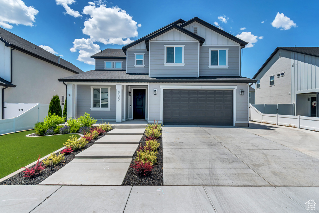 View of front facade with concrete driveway, an attached garage, covered porch, and board and batten siding